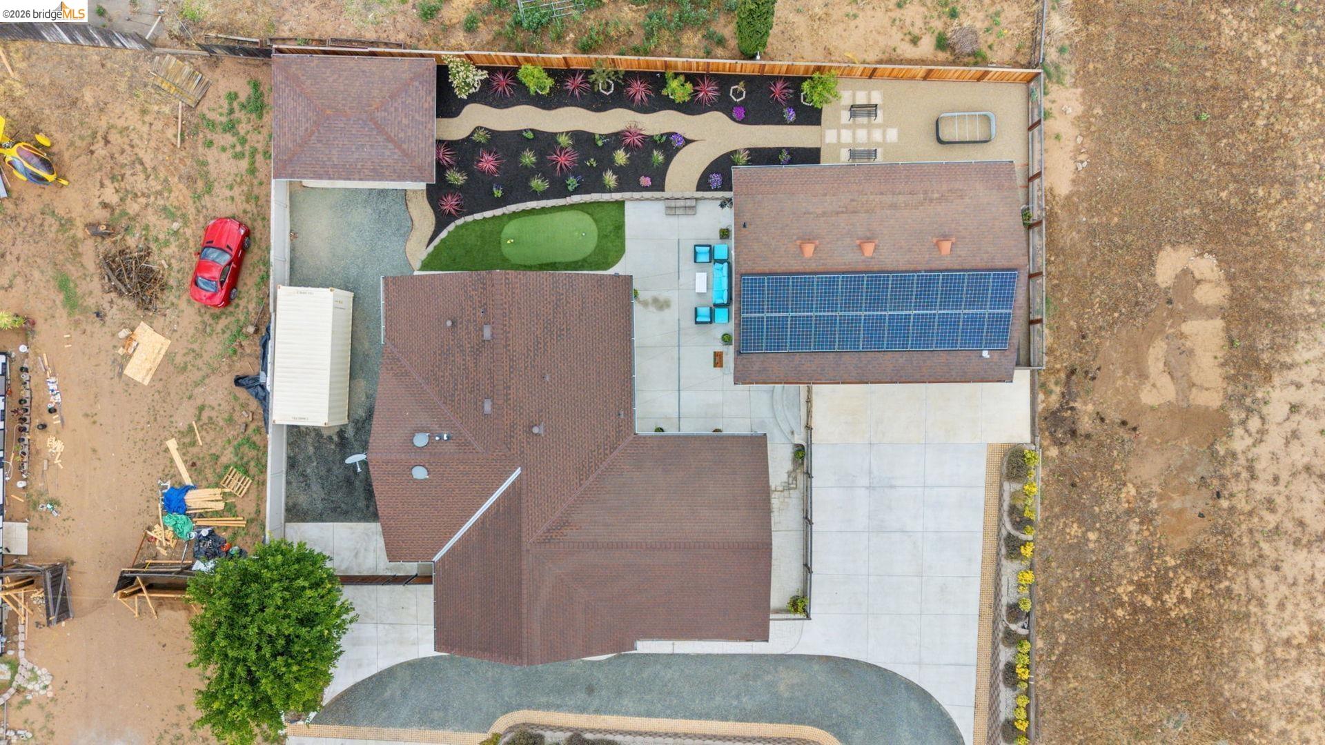 700 Brownstone Road Oakley, CA 94561 - Photo 3 of 58 Expansive aerial view showcasing a multi-gabled roofline, solar panel array, paved driveway, dedicated putting green, and landscaped garden beds with decorative rock