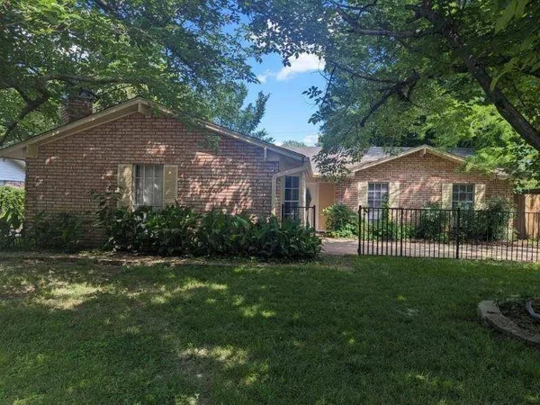 a view of a house next to a big yard and large trees