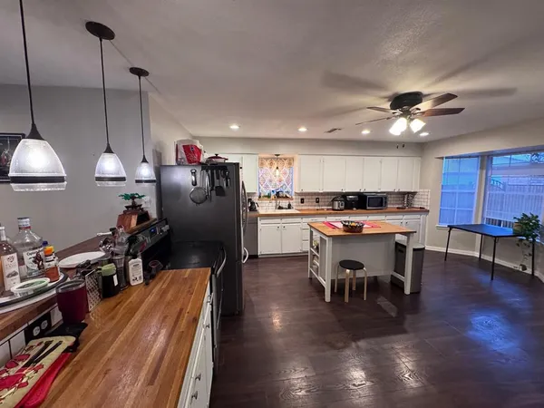 a kitchen with stainless steel appliances a dining table chairs stove and a bookshelf