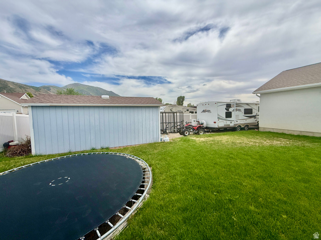 1353 360 West Payson, UT 84651 - Photo 16 of 16 Expansive backyard featuring a green lawn, a light blue storage shed with a brown shingle roof, and a white vinyl privacy fence