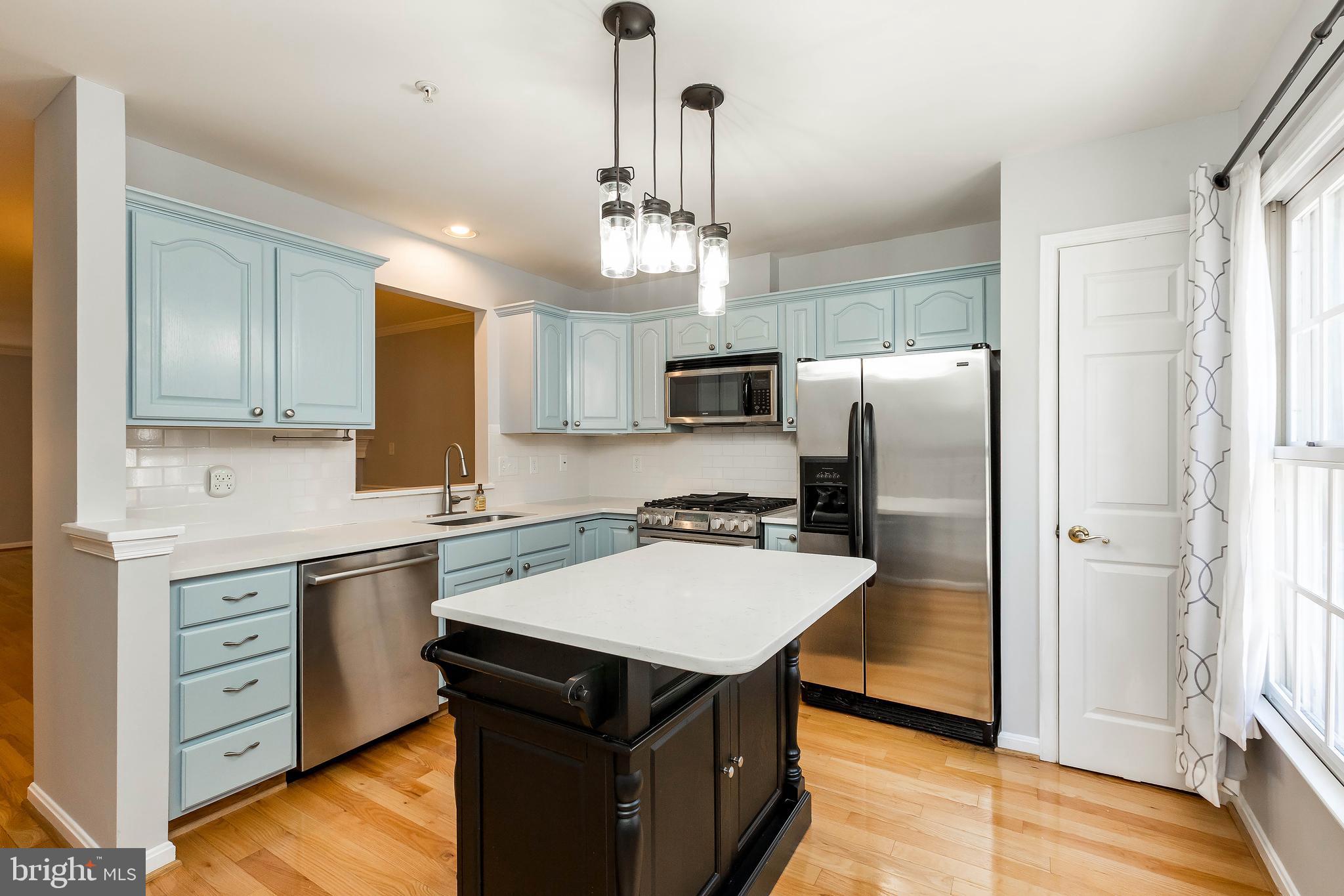 205 Ridgepoint Place Gaithersburg, MD 20878 - Photo 20 of 51 a kitchen with a refrigerator a sink dishwasher a kitchen island with wooden cabinets and floor