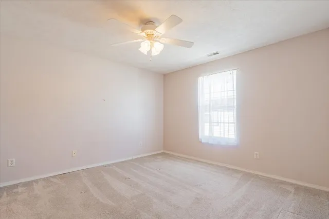 an empty room with windows and chandelier fan