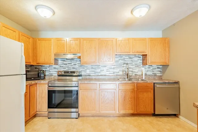 a kitchen with stainless steel appliances granite countertop a stove a sink and a refrigerator