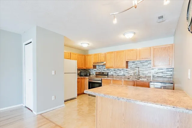 a kitchen with a stove a refrigerator a sink a counter top space and cabinets