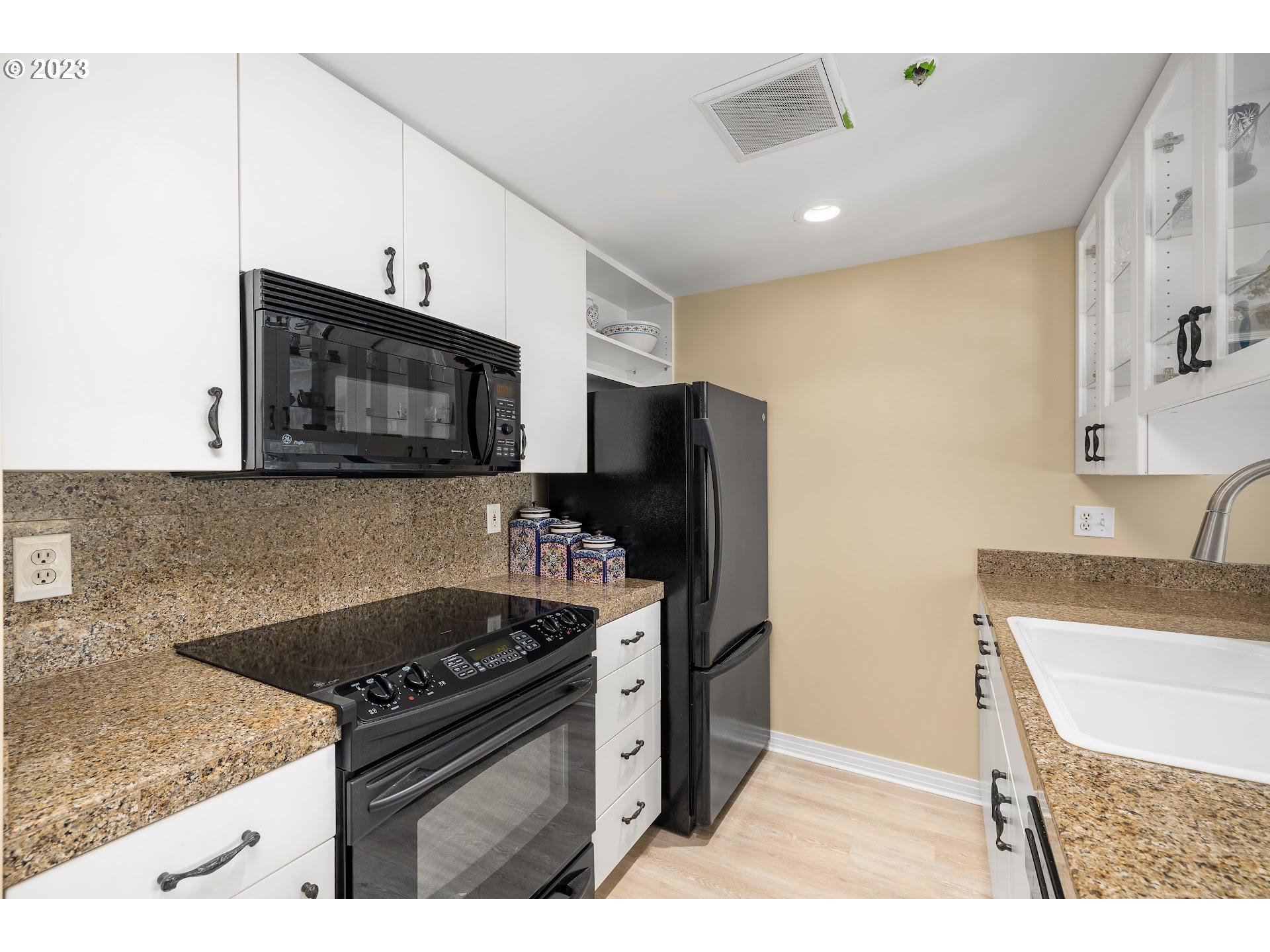 1132 Southwest 19th Avenue, Unit 406 Portland, OR 97205 - Photo 16 of 38 a kitchen with granite countertop a sink stove and refrigerator