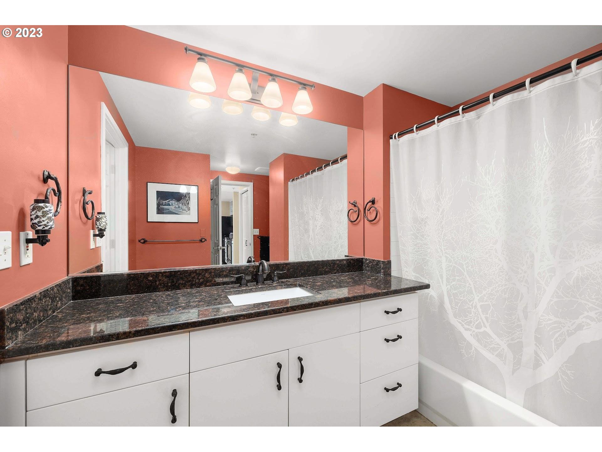 1132 Southwest 19th Avenue, Unit 406 Portland, OR 97205 - Photo 25 of 38 a bathroom with a granite countertop sink and a mirror