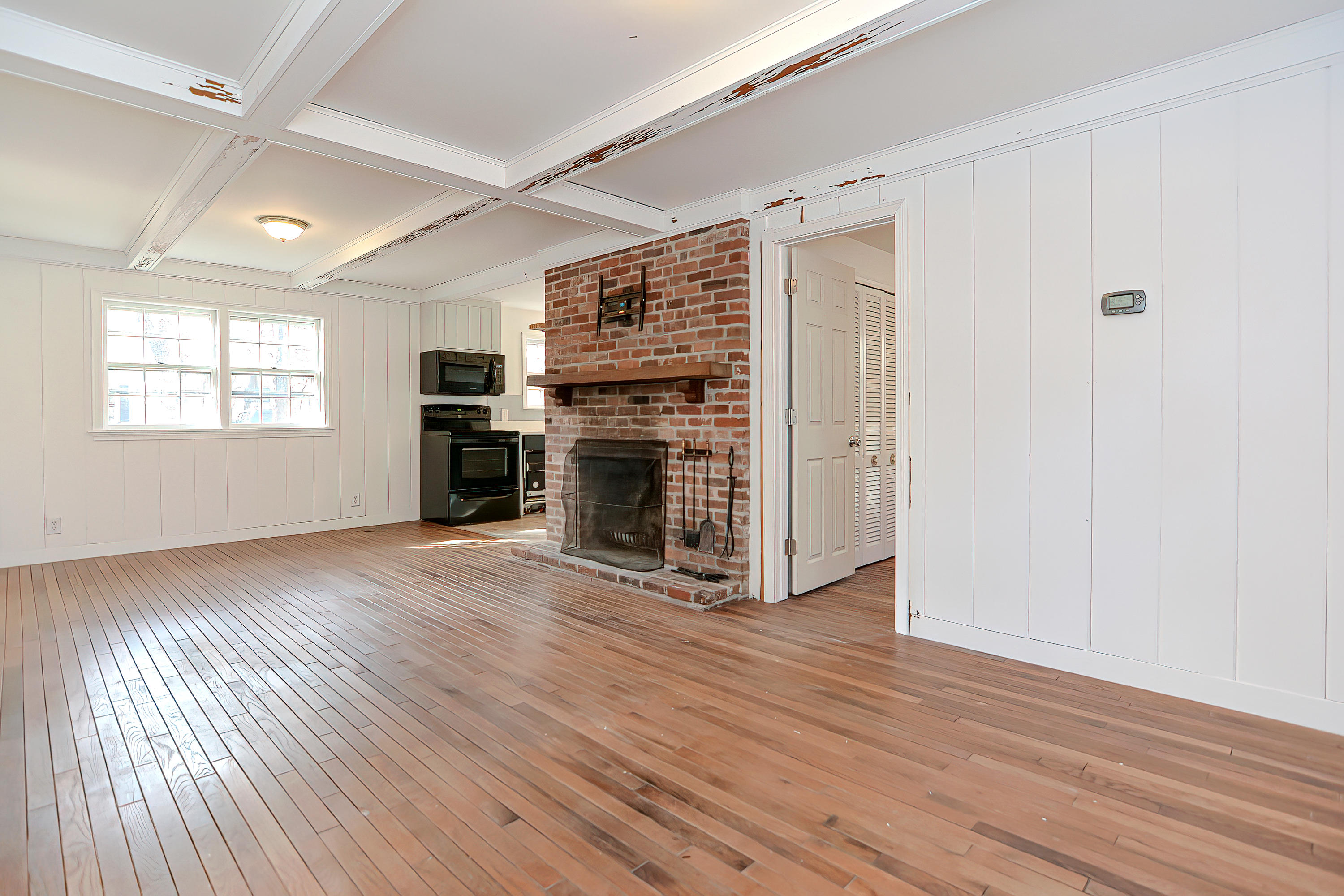 321 Monomoscoy Road Mashpee, MA 02649 - Photo 8 of 43 an empty room with wooden floor fireplace and windows