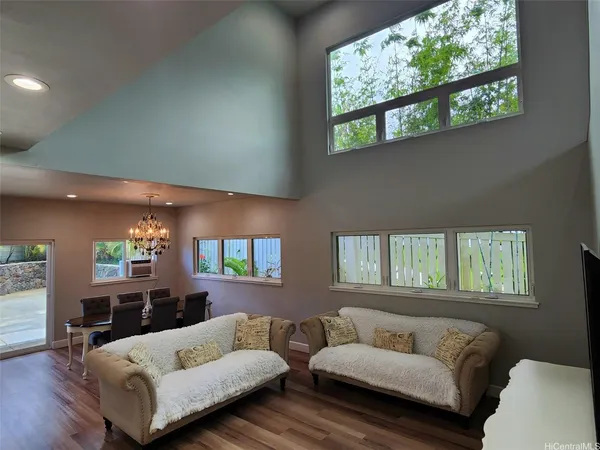 a view of a dining room with furniture a chandelier and large windows