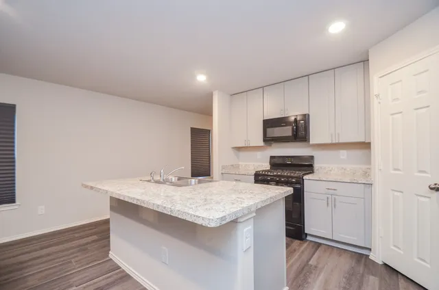 a kitchen with granite countertop a sink stove and refrigerator