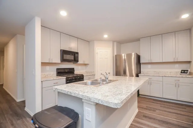 a kitchen with granite countertop a sink stove and refrigerator