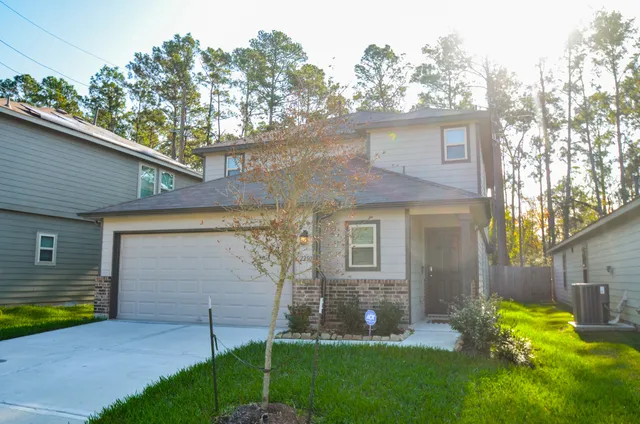 a front view of a house with a yard and a large tree