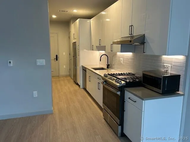 a kitchen with granite countertop a refrigerator a sink a stove and cabinets