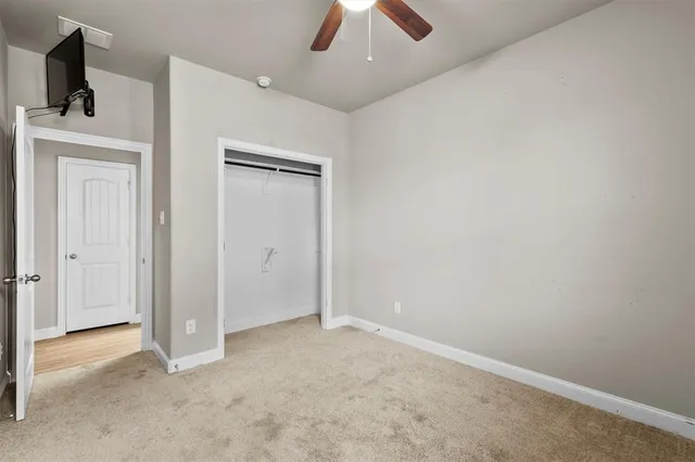 an empty room with closet and a chandelier fan