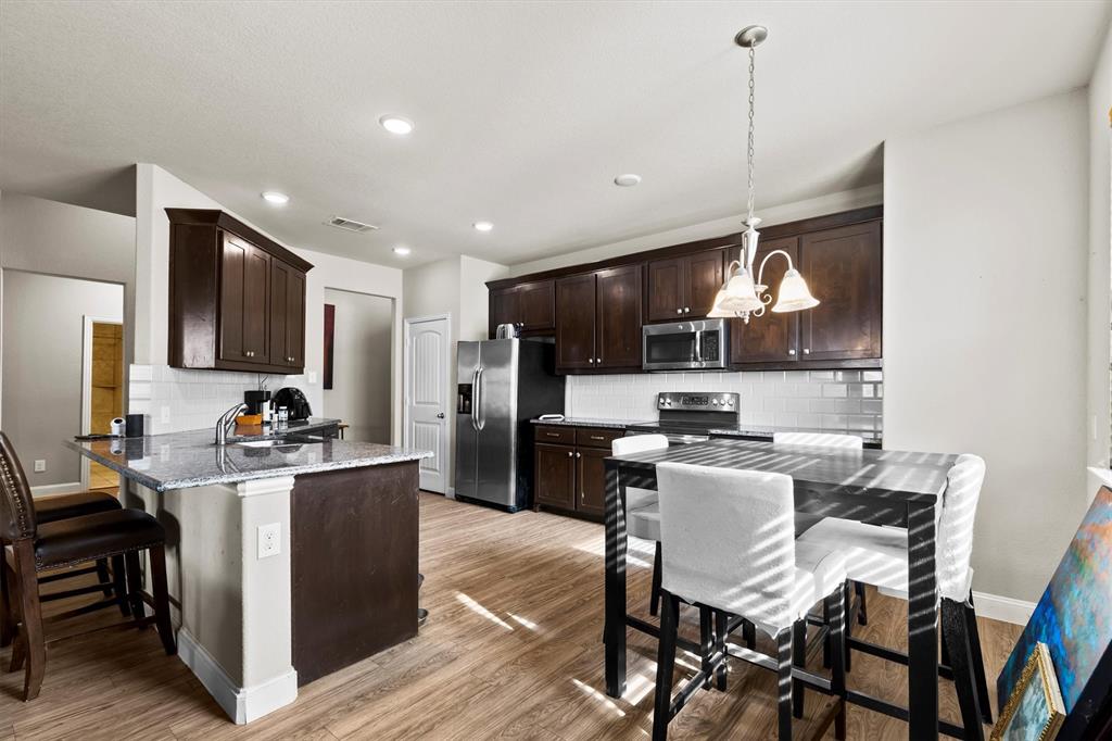 11 Pleasant Valley Sanger, TX 76266 - Photo 6 of 20 a kitchen with a table chairs refrigerator and microwave