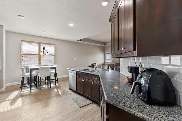 a kitchen with granite countertop a stove a sink a dining table and chairs