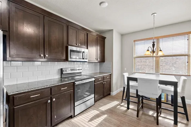a kitchen with stainless steel appliances granite countertop wooden floors and wooden cabinets