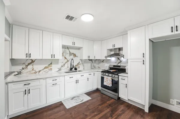 a kitchen with granite countertop white cabinets and stainless steel appliances
