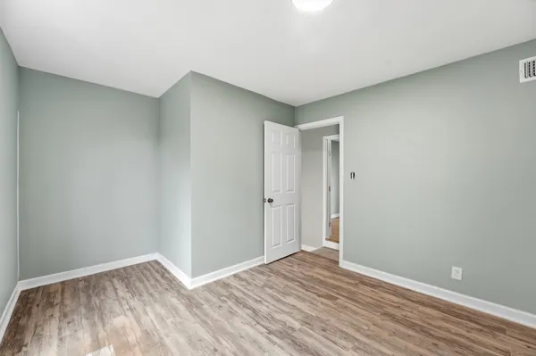 a view of an empty room with wooden floor and closet