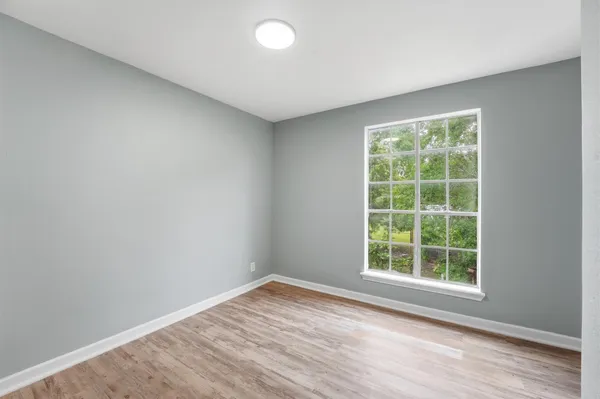 an empty room with wooden floor and windows