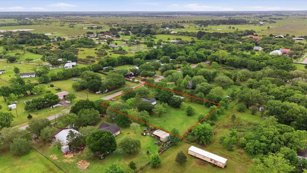 an aerial view of residential houses with outdoor space and trees