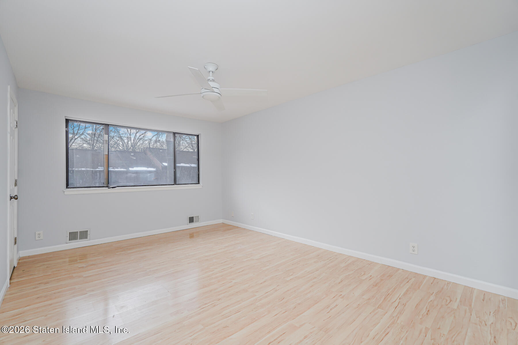 1818 Forest Hill Road Staten Island, NY 10306 - Photo 15 of 36 an empty room with wooden floor and windows