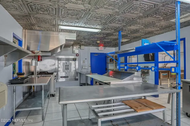 a kitchen with stainless steel appliances kitchen island granite countertop a table chairs sink and cabinets