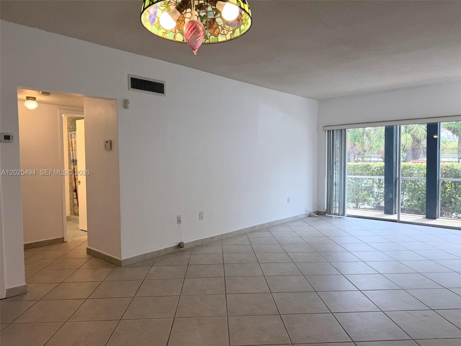 9159 Southwest 77th Avenue, Unit 112 Miami, FL 33156 - Photo 17 of 38 an empty room with windows and chandelier