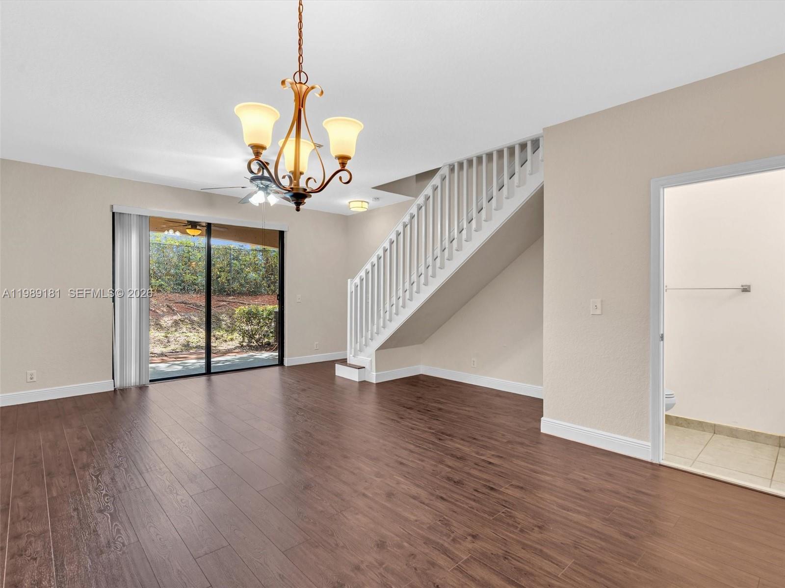 4126 Forest Drive Weston, FL 33332 - Photo 12 of 37 a view of an empty room with wooden floor and a chandelier