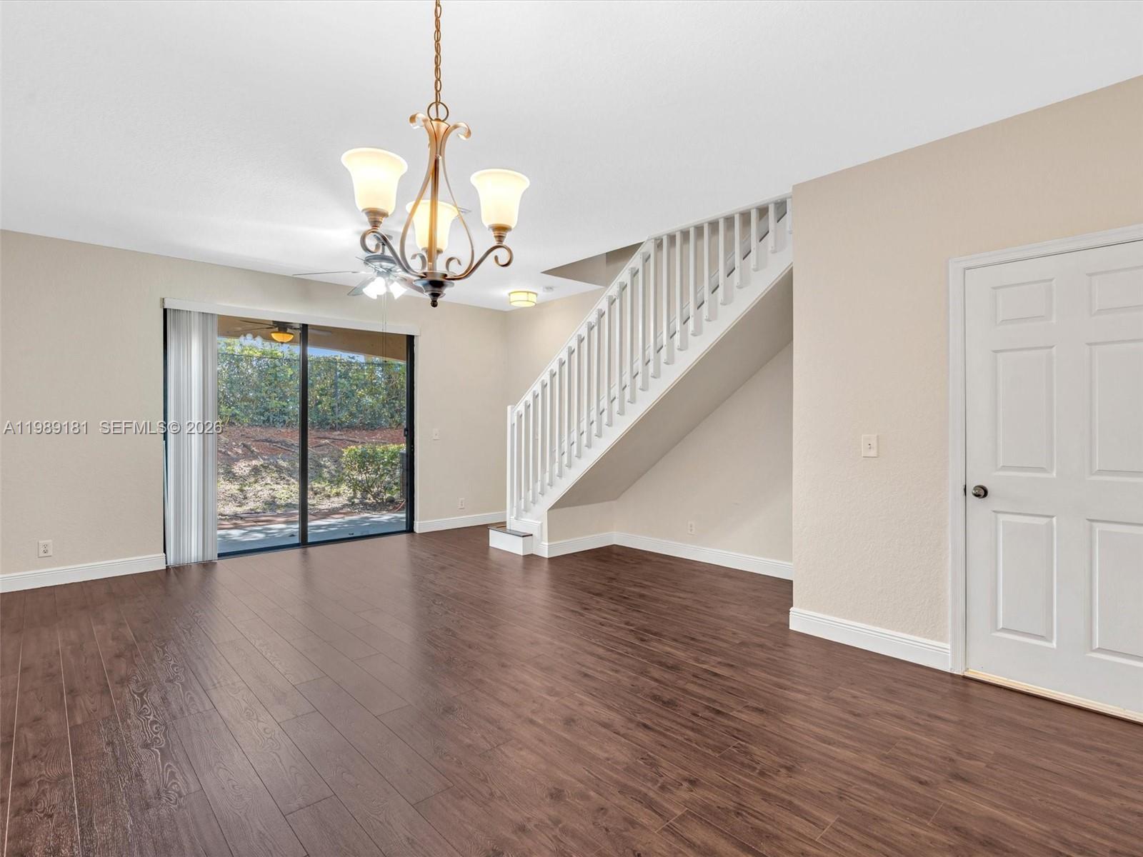 4126 Forest Drive Weston, FL 33332 - Photo 14 of 37 a view of an empty room with wooden floor and a chandelier