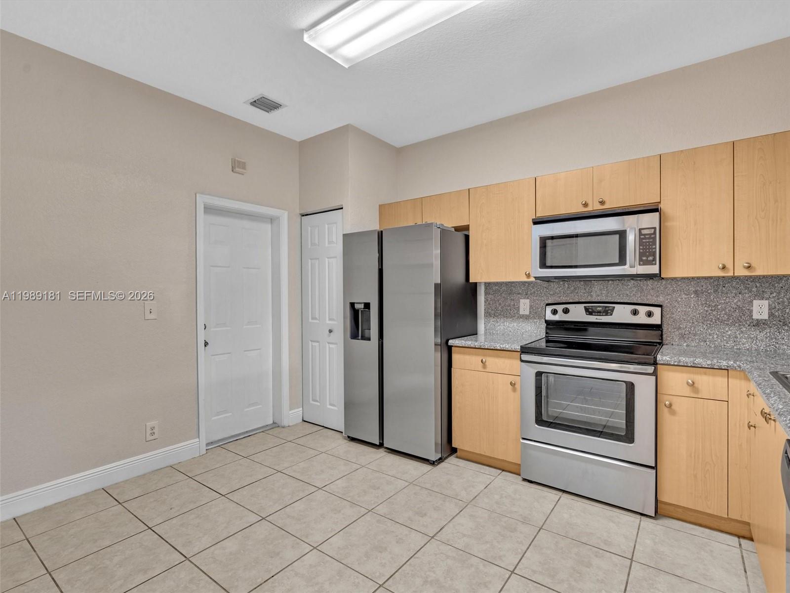 4126 Forest Drive Weston, FL 33332 - Photo 4 of 37 a kitchen with granite countertop a stove and a refrigerator with white cabinets