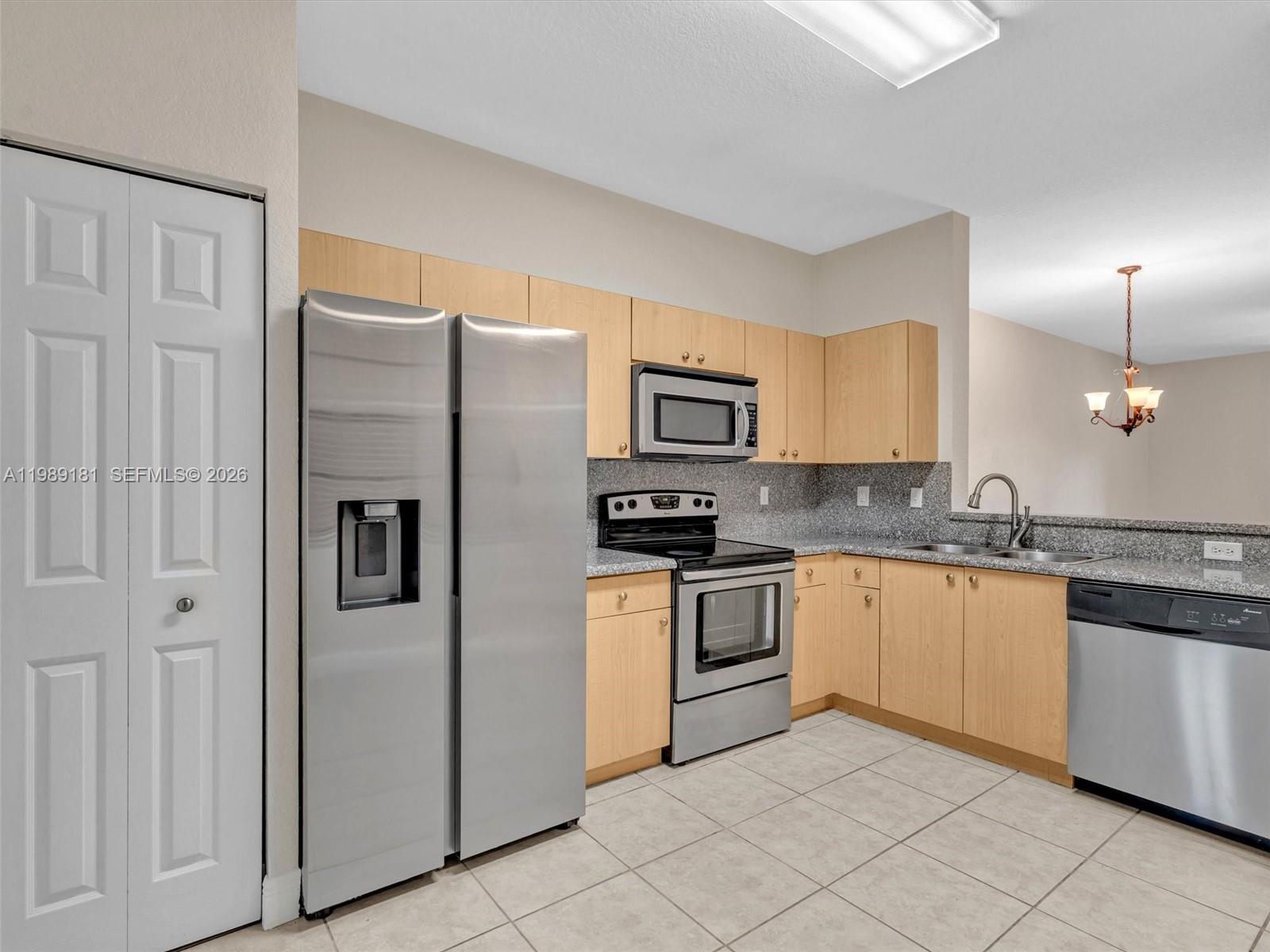 4126 Forest Drive Weston, FL 33332 - Photo 5 of 37 a kitchen with granite countertop white cabinets and white appliances
