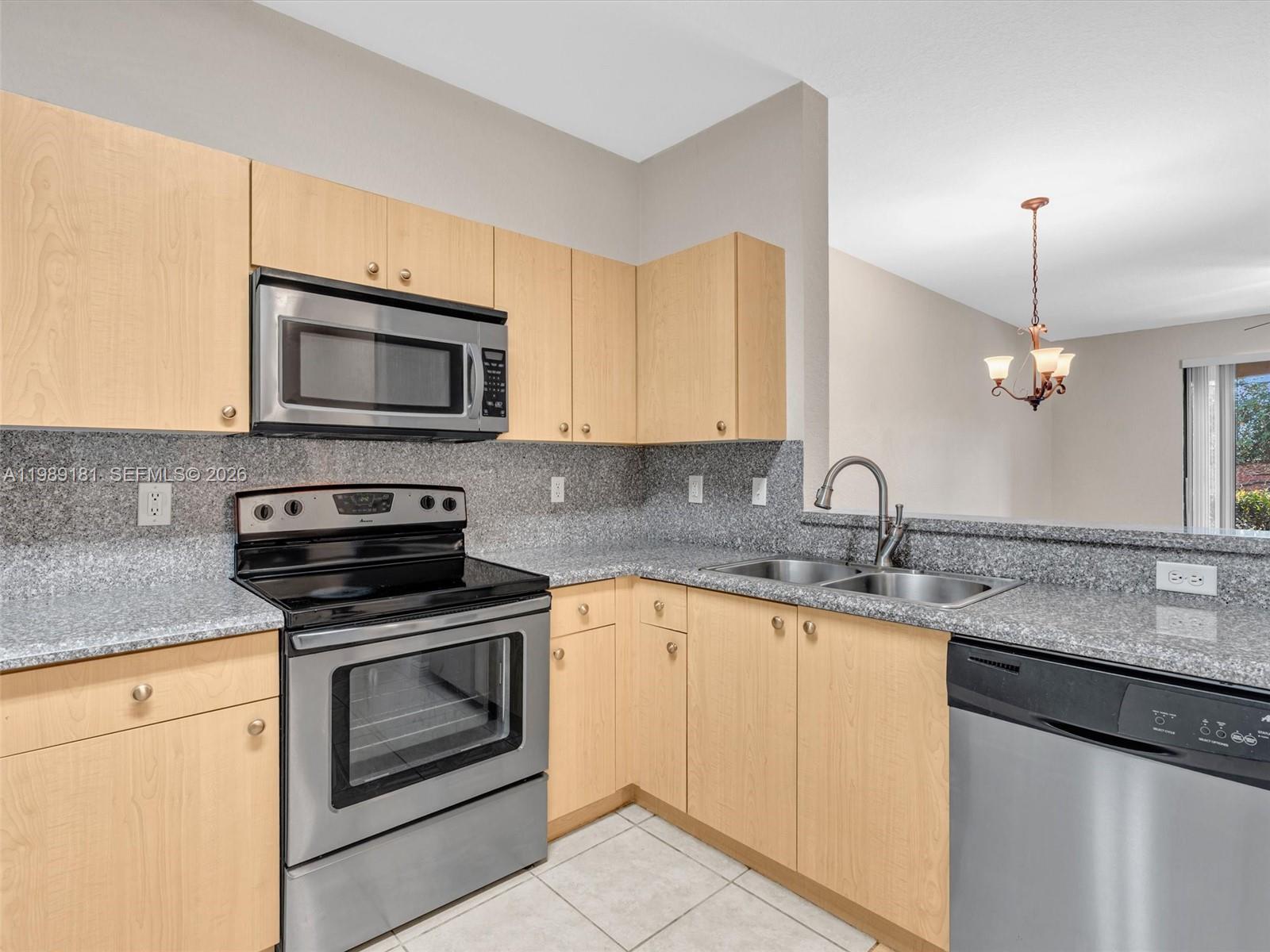 4126 Forest Drive Weston, FL 33332 - Photo 6 of 37 a kitchen with granite countertop a sink stainless steel appliances and white cabinets