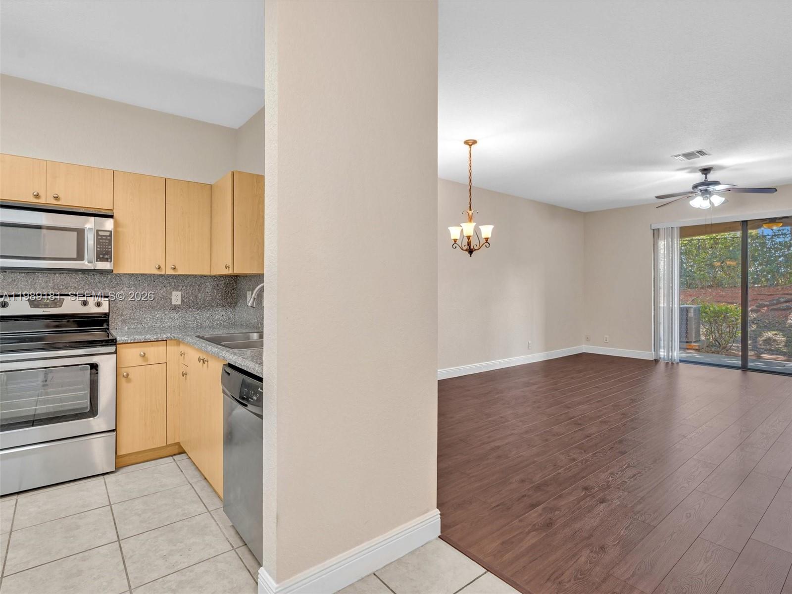 4126 Forest Drive Weston, FL 33332 - Photo 7 of 37 a kitchen with granite countertop a stove a sink and white cabinets with wooden floor