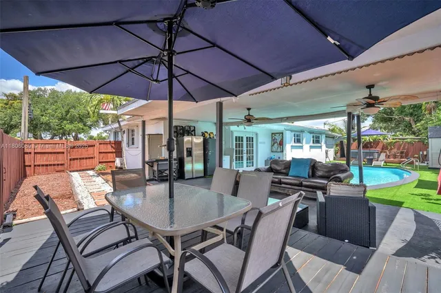 a view of a patio with table and chairs under an umbrella with wooden floor
