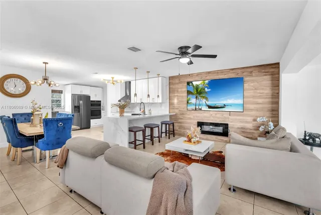 a living room with furniture a fireplace kitchen view and a flat screen tv