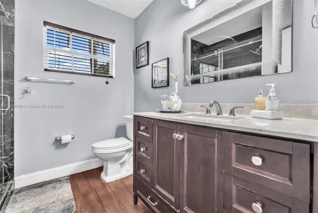 a bathroom with a granite countertop toilet sink and mirror