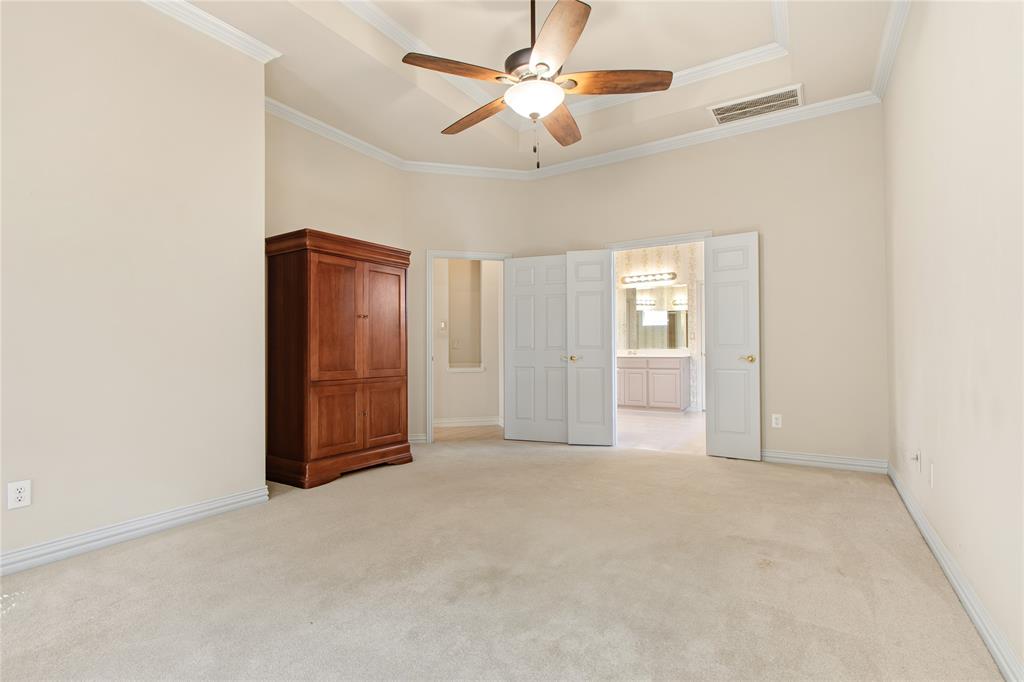 1614 Villa Court Corinth, TX 76210 - Photo 11 of 17 Unfurnished bedroom featuring light carpet, ceiling fan, crown molding, a raised ceiling, and a towering ceiling