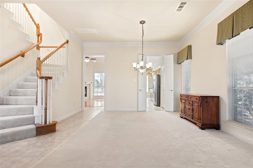 1614 Villa Court Corinth, TX 76210 - Photo 2 of 17 Unfurnished living/dining area featuring light tile patterned floors, ornamental molding, a chandelier, stairs, and light-colored carpet