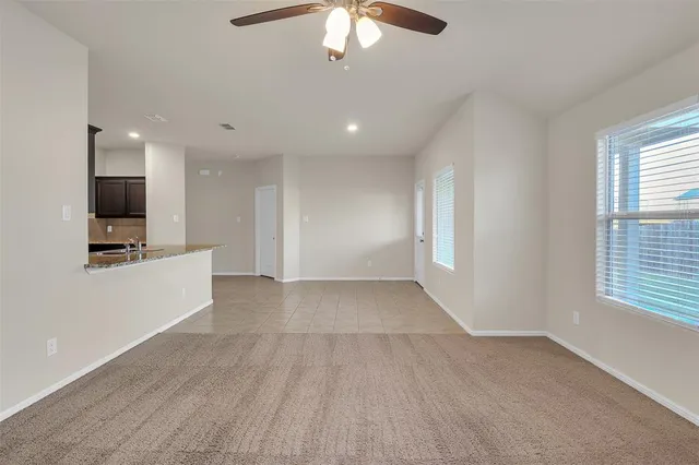 a view of an empty room with a window and a kitchen