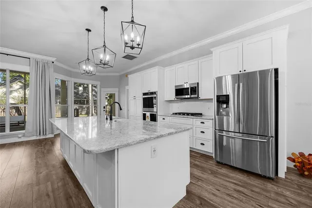 a kitchen with stainless steel appliances granite countertop a refrigerator a stove top oven a refrigerator cabinets and wooden floor