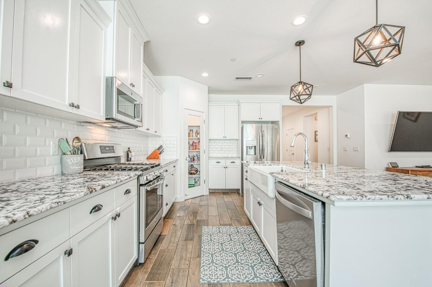 408 Grant Avenue West Madera, CA 93636 - Photo 12 of 42 a large kitchen with stainless steel appliances granite countertop a stove oven and a white cabinets