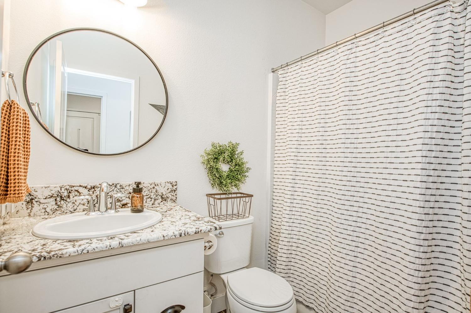408 Grant Avenue West Madera, CA 93636 - Photo 18 of 42 a bathroom with a granite countertop toilet a sink and a mirror