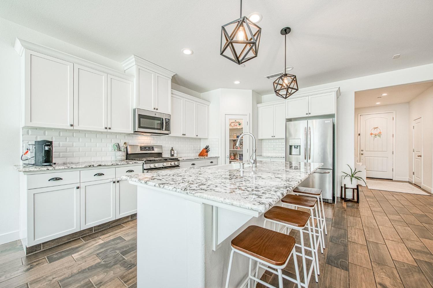 408 Grant Avenue West Madera, CA 93636 - Photo 10 of 42 a kitchen with stainless steel appliances granite countertop a sink a stove a refrigerator cabinets and chairs