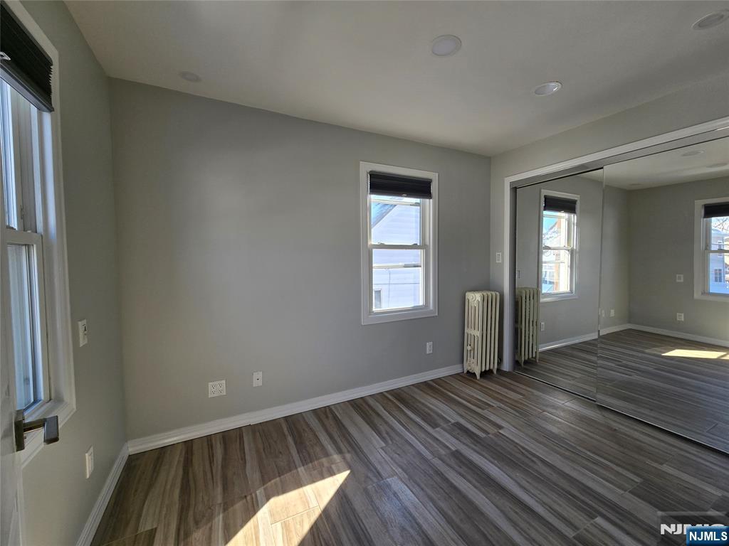 282 Harding Avenue, Unit 2 Teaneck, NJ 07666 - Photo 12 of 17 an empty room with wooden floor and windows