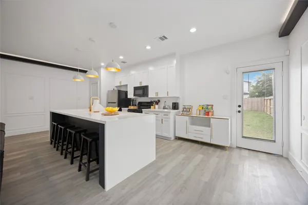 a kitchen with kitchen island wooden floors and stainless steel appliances