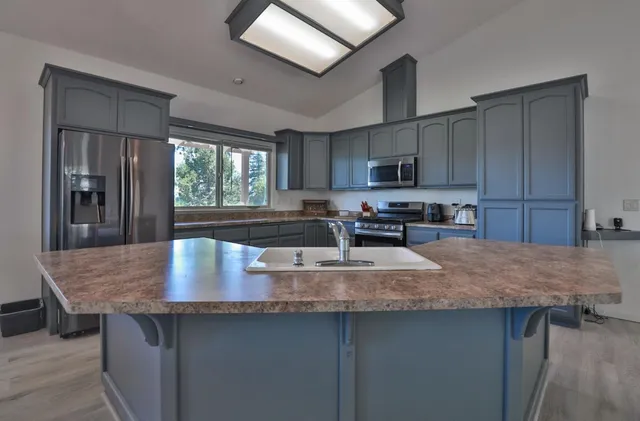 a kitchen with kitchen island granite countertop a stove a sink and a granite counter tops