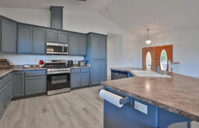 a kitchen with stainless steel appliances granite countertop a stove a sink and a microwave