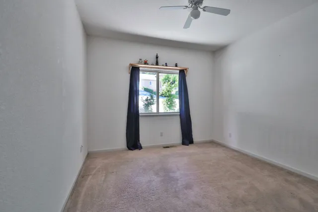an empty room with a window and a ceiling fan