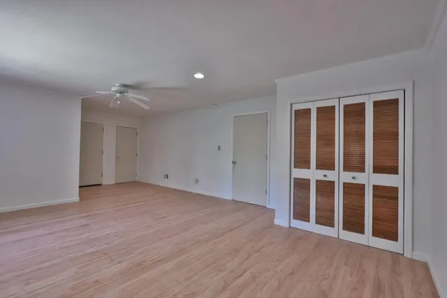 a view of an empty room with wooden floor and windows