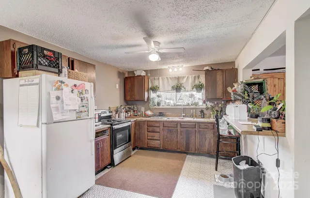 a kitchen with a refrigerator a stove a sink a dining table and chairs